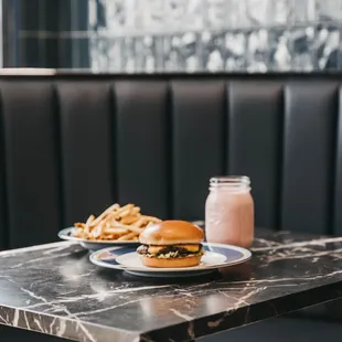 two plates of burgers and a jar of milk