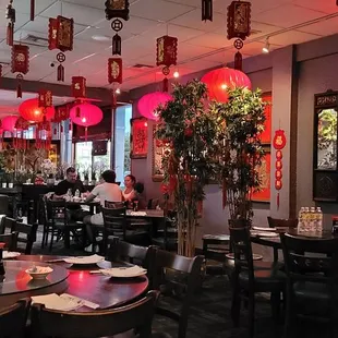 tables and chairs with red lanterns hanging from the ceiling