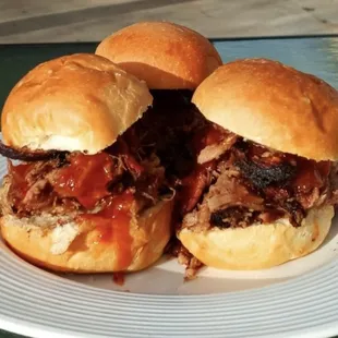 three pulled pork sandwiches on a plate