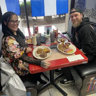 two people sitting at a table with plates of food