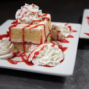 a slice of cake with whipped cream and red sauce