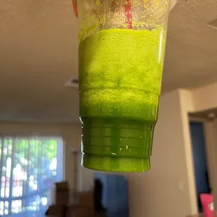  a person holding a cup of green juice