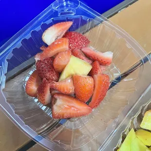 strawberries and pineapples in a plastic container