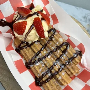 Churros topped with vanilla ice cream and strawberries