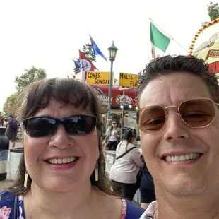 a man and a woman standing in front of a carnival