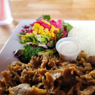 a plate of meat, rice, and a salad
