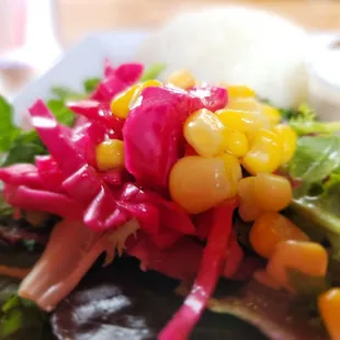 a colorful salad with corn, lettuce, and other vegetables