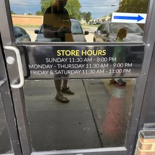 a store hours sign on a glass door