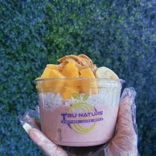 a hand holding a cup of fruit smoothie