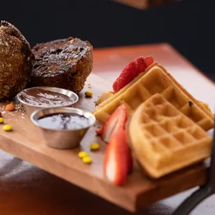 a plate of waffles, strawberries, and fruit