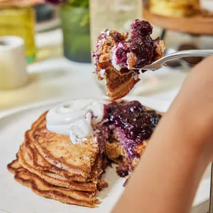 a plate of pancakes with blueberries and whipped cream