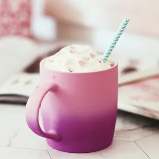 a cup of coffee with whipped cream and a straw