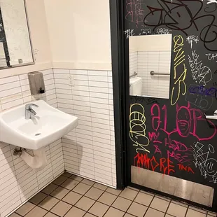 a bathroom with graffiti on the walls