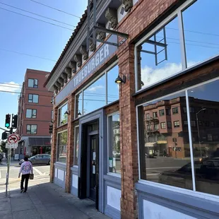 a woman walking down the sidewalk in front of a building