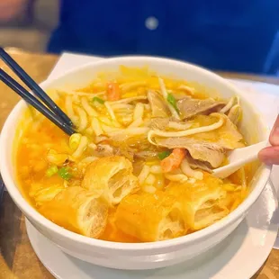 a bowl of soup with chopsticks