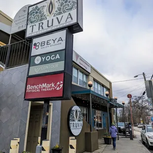 Outside. Storefront. Street sign for building. Dedicated parking lot on-site. You have to pay during certain hours.