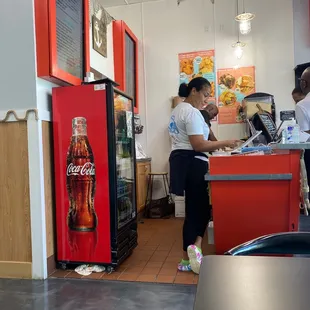 a woman standing at a counter in a fast food restaurant