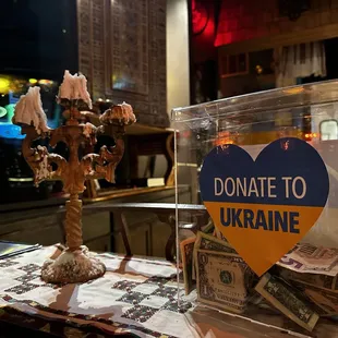 Donation box for Ukraine and striking candleholder with some burnt candles.