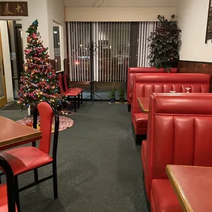 a restaurant with red booths and a christmas tree