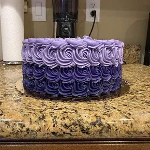 Three different shades of purple rosettes on a strawberry cake with churro frosting.