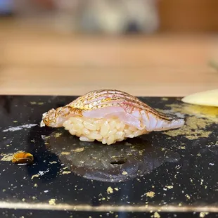 a piece of sushi on a black plate
