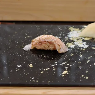 a piece of sushi on a black plate