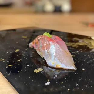a piece of sushi on a black plate