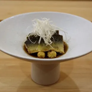a white bowl of food on a wooden table