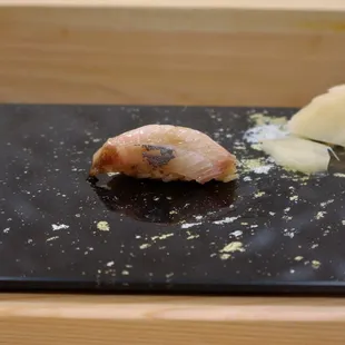 a piece of sushi on a black plate