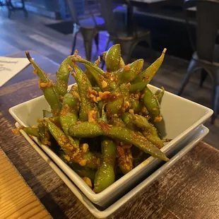 a bowl of green beans on a wooden table