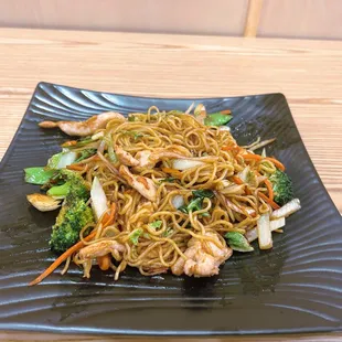 a plate of noodles with shrimp and broccoli