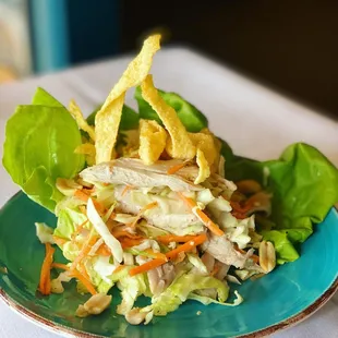 a salad with chicken, lettuce, carrots, and tortillas