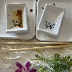 two dishes with chopsticks and a flower