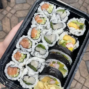 a person holding a tray of sushi