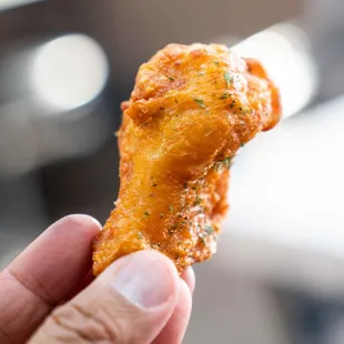 a hand holding a piece of fried chicken