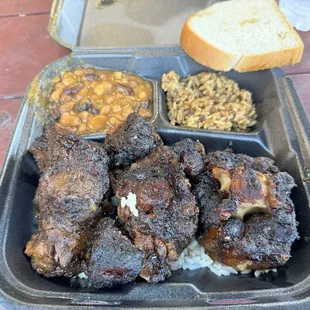 Oxtails plate with baked beans and dirty rice.