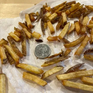 Hand cut french fries next to a quarter.