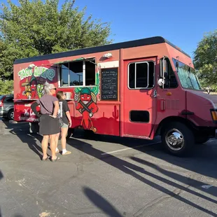 two people standing in front of a food truck
