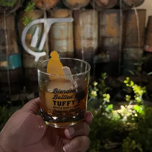 a hand holding a glass of whiskey