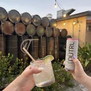 two hands holding a drink and a can