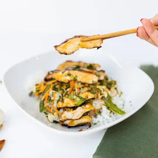 a person holding a chopstick over a bowl of food