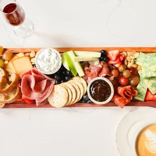 Our Charcuterie board featuring: Cured meats, artisan cheeses, Marcona almonds, fresh fruit, and fig jam, served with crostini and crackers.