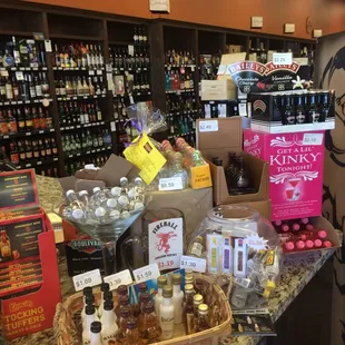 a woman standing in front of a counter full of bottles of wine
