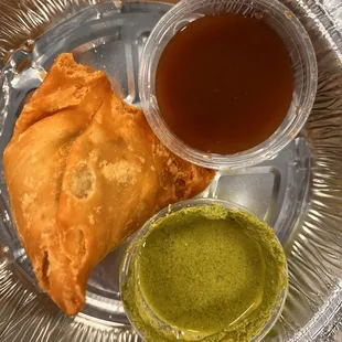 Samosa as part of take out order. Finely textured filling, piquant sauces