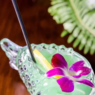 a green drink with a purple flower