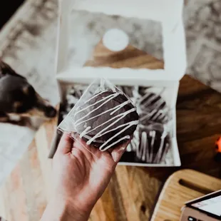 a person holding a chocolate covered doughnut