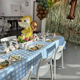a table with plates of food and balloons