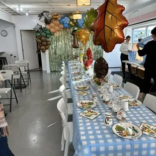a table with plates of food and balloons
