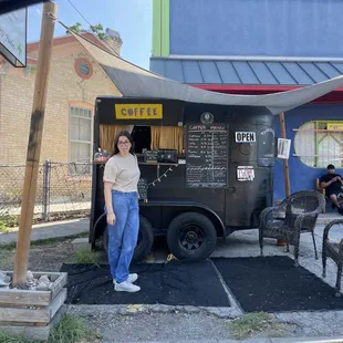 a woman standing in front of a coffee truck