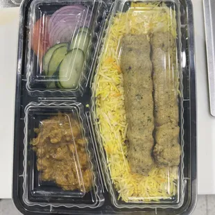 Seekh Kakab served on a bed of basmati rice w/chola curry and veggie salad